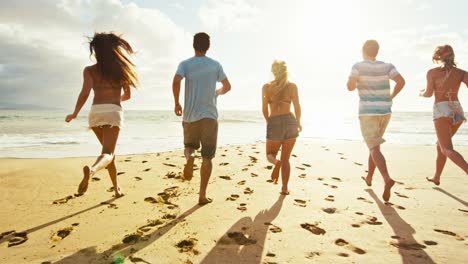 Group-of-friends-having-fun-walking-down-the-beach-at-sunset