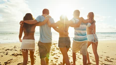 Group-of-friends-having-fun-walking-down-the-beach-at-sunset