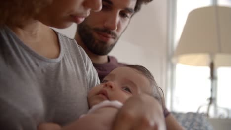 Eltern-kuscheln-Baby-Tochter-in-Schlafzimmer-zu-Hause