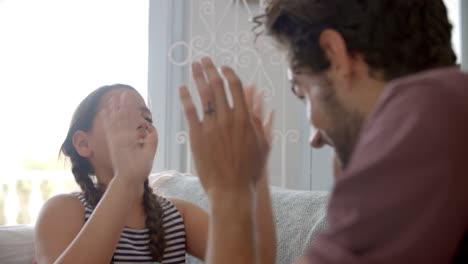 Vater-und-Tochter-spielen-Klappspiel-auf-Sofa