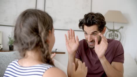 Vater-und-Tochter-spielen-Klappspiel-auf-Sofa