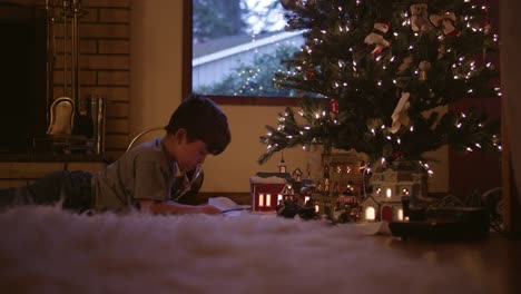 Pequeño-niño-armar-las-vías-del-tren-en-frente-del-árbol-de-Navidad