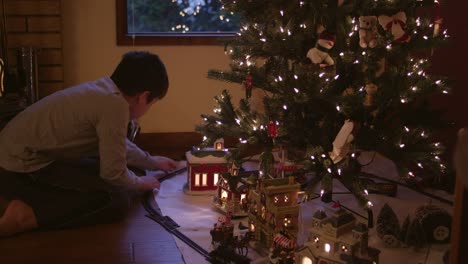 Kleiner-Junge-Zusammenstellung-Schienen-vor-dem-Weihnachtsbaum