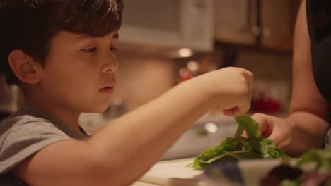 A-little-boy-helping-his-mom-prepare-food-in-the-kitchen,-close-up