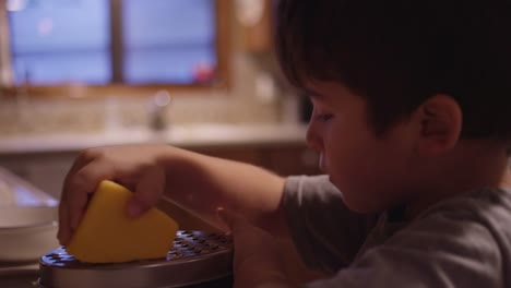 Un-niño-pequeño-rallador-queso-en-la-cocina