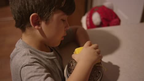 A-little-boy-shredding-cheese-in-the-kitchen