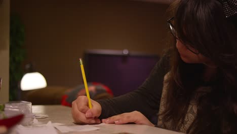 A-girl-sitting-at-a-kitchen-counter-writing-on-a-piece-of-paper