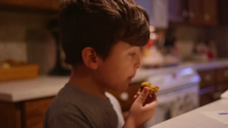 A-little-boy-eating-a-pastry-in-the-kitchen