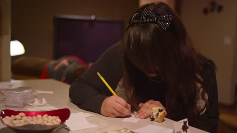 A-girl-sitting-at-a-kitchen-counter-writing-on-a-piece-of-paper