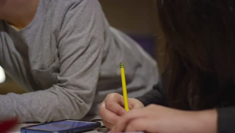 A-little-boy-looks-over-his-sister's-shoulder-while-she-draws