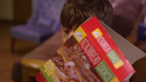 A-little-boy-cutting-open-a-cardboard-box-with-scissors