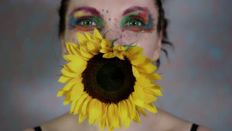 4k-Shot-of-a-Woman-with-Multicoloured-Make-up-With-Sunflower-(focus-on-flower)