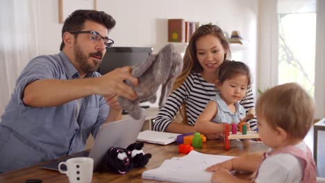 Vater-nutzt-Laptop-während-Mutter-mit-Kindern-zu-Hause-spielt