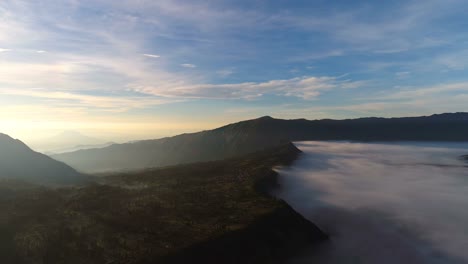 Aerial-view-flight-over-Cemoro-Lawang,-small-village-in-morning-mist.