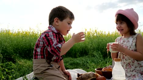 Glückliche-Kinder-in-frischer-Luft,-Brot-und-Milchprodukte-essen,-während-im-übrigen-Freunde-auf-grünen-Rasen,-Kinder-bei-Picknick,-Familie-trinkt-Milch