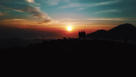 Personas-de-pie-en-la-cima-de-volcán-activo-Monte-Batur-en-Bali-al-amanecer-con-nubes-revelan-tiro-aéreo-4-K