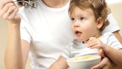 Mother-giving-food-to-her-child-at-home.-Close-up-view.