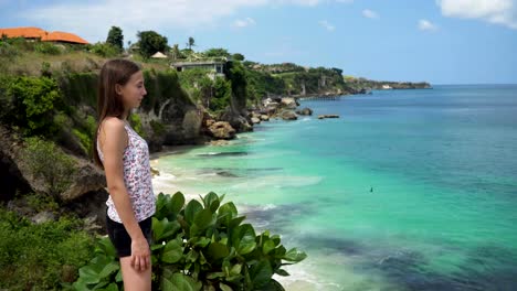 Girl-standing-on-a-cliff-and-looking-at-the-sea.-Bali,-Indonesia