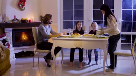 Glückliche-Familie-hat-ein-festliches-Dinner-auf-dem-Weihnachtstisch