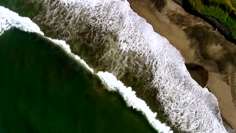 Aerial-view-waves-break-on-white-sand-beach.