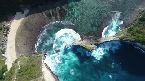 Aerial-view-by-drone-4k-camera.-Rocks-in-a-blue-sea-lagoon-with-breaking-waves.