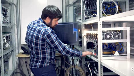 IT-engineer-working-in-cryptocurrency-mining-factory.-Industrial-mining-farm-for-bitcoin-and-cryptocurrency-money.