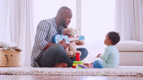 Joven-padre-negro-tocando-el-ukelele-con-hijo-en-sala-de-estar