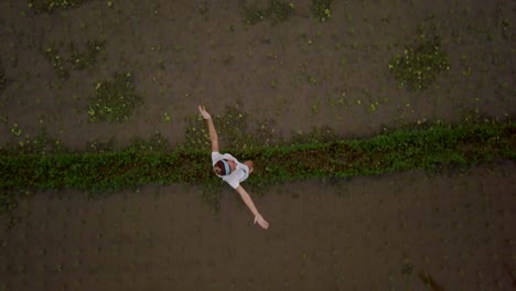 Young-woman-standing-infant-of-rice-terrace-in-Bali-arms-outstretched.-Woman-arms-outstretched-in-nature,-Southeast-Asia.-Drone-Shot