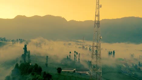 Mist-flowing-into-vast-landscapes-of-Mount-Bromo-at-sunset-an-aerial-view,-indonesia