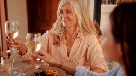 Mujer-madura-brindando-con-vino-durante-el-almuerzo-en-el-restaurante-rústico