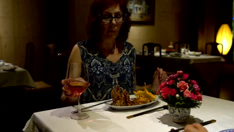 Mujer-sentada-en-una-mesa-en-el-restaurante-comer,-hablar,-chokaetsja-un-vaso-y-beber-vino-tinto