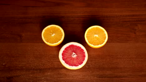 Girl-puts-on-a-wooden-table-half-ripe-grapefruit.