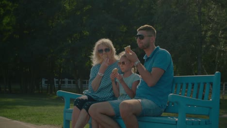 Multi-generation-family-eating-ice-creams-on-bench