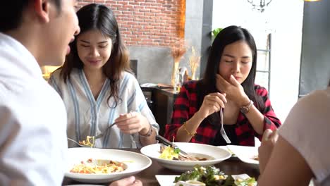 Group-of-Four-young-Asian-people,-one-man,-three-women,-eating-and-talking-at-cafe-and-restaurant.-Friendship-concept