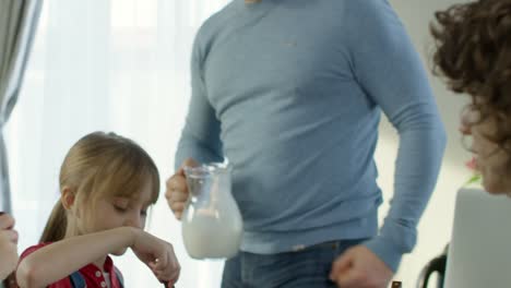 Vater-gießt-Milch-in-Schalen-von-Getreide