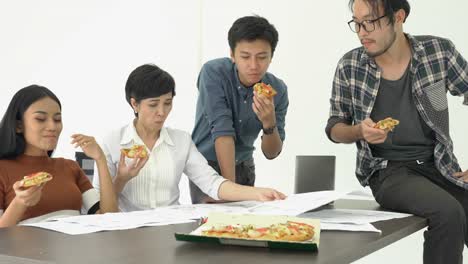 Gente-de-negocios-comer-pizza-es-tiempo-de-descanso-y-reunión-equipo-junto-para-proyecto-de-éxito.-Concepto-de-trabajo-en-equipo,-relax,-trabajo-creativo-y-compartir-la-idea.