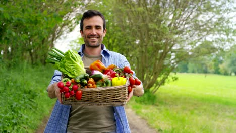 Porträt-eines-glücklichen-jungen-Landwirts-mit-frischem-Gemüse-in-einen-Korb.-Auf-Grund-der-Natur.