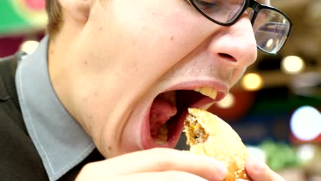 Un-joven-está-comiendo-una-hamburguesa-en-un-centro-comercial.