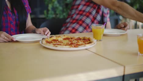 hombre-está-cuidando-a-una-mujer-en-la-pizzería-en-fecha.-Las-manos-del-hombre-están-poniendo-un-plato-y-cubiertos-para-mujer