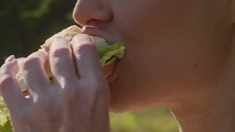 woman-biting-off-and-chewing-burger-on-the-street