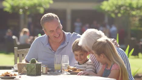 Großeltern-mit-Enkeln-genießen-Outdoor-Sommer-Pub-Mittagessen