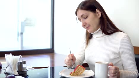 Mujer-hermosa-bebe-café-y-come-pastel-de-café.