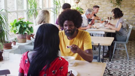 Negro-pareja-adultos-hablando-sobre-brunch-en-un-restaurante-ocupado-cerca