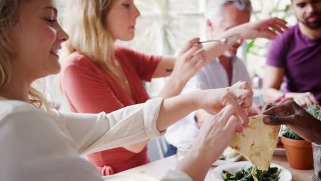 Un-grupo-de-edad-mixto-de-amigos-adultos-compartir-tapas-en-una-mesa-en-un-restaurante,-enfoque-selectivo,-enfoque-en-primer-plano