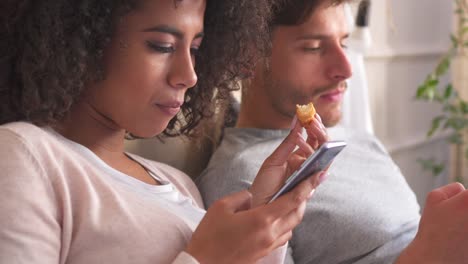 Couple-using-mobile-phone-during-breakfast-on-bed