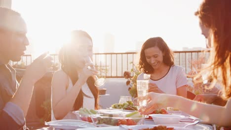 Amigos-se-reunieron-en-la-terraza-de-la-azotea-para-comida-con-el-horizonte-de-la-ciudad-en-segundo-plano