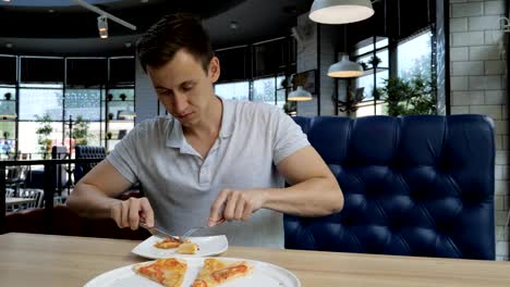 Schönen-jungen-Mann-Essen-Pizza-in-einem-café