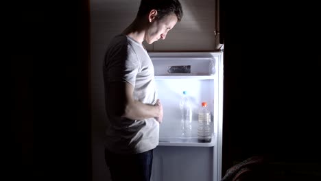 young-man-has-a-banana-at-the-fridge-at-night