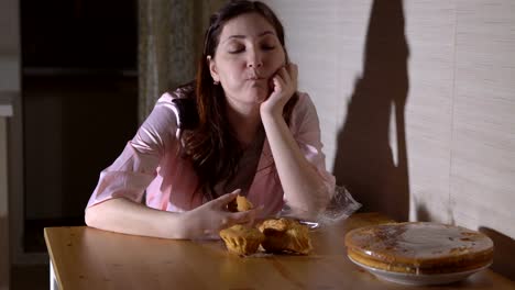 Young-woman-at-night-in-the-kitchen-eating-a-bun