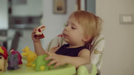 kleiner-Junge-sitzt-auf-Hochstuhl-Sandwich-zu-essen